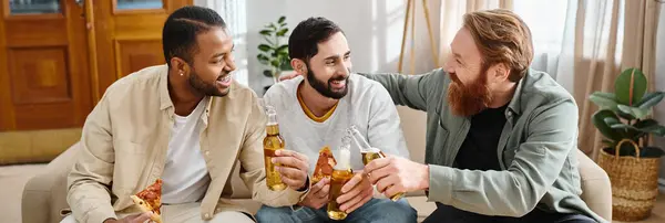 Tres hombres alegres y elegantes con cerveza relajándose en un sofá, exudando camaradería y amistad. - foto de stock