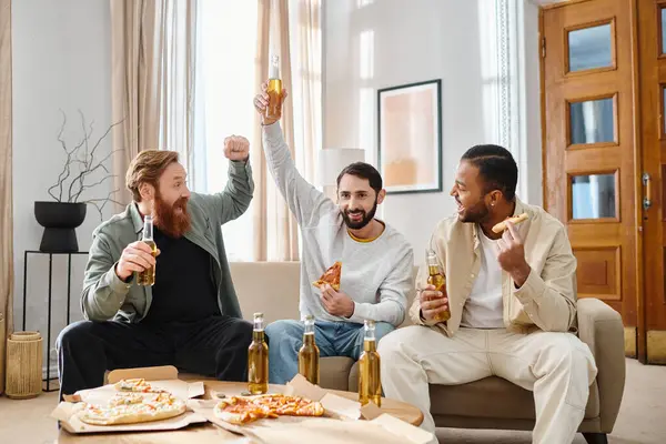 Trois beaux hommes de différentes races s'assoient sur un canapé, dégustant pizza et bière ensemble dans une atmosphère décontractée et conviviale. — Photo de stock