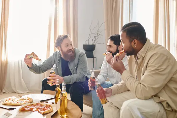 Three cheerful, handsome men of different ethnicities laughing and eating pizza together at a table in casual attire. — Stock Photo