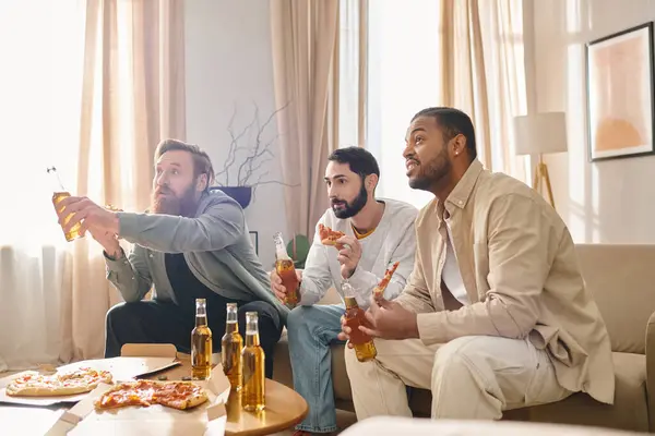 Трое красивых межрасовых мужчин в повседневной одежде, отлично проводят время вместе, сидят за столом и наслаждаются пивом. — стоковое фото