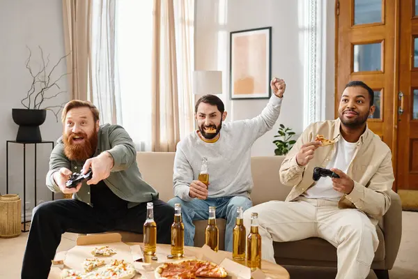 Trois beaux hommes interraciaux en tenue décontractée s'assoient autour d'une table avec pizza et bière, riant et s'amusant. — Photo de stock