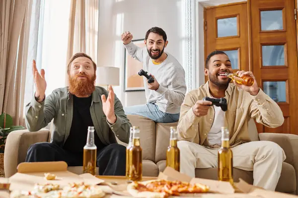 Trois hommes beaux et joyeux de différentes races s'assoient autour d'une table, dégustant des pizzas et se côtoyant dans un cadre décontracté. — Photo de stock