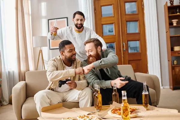 Tres hombres guapos e interraciales con atuendo casual se sientan alegremente alrededor de una mesa con cerveza, compartiendo risas y camaradería. - foto de stock