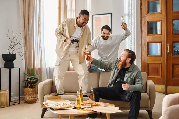Три веселых, межрасовых мужчины в повседневной одежде стоят вместе в гостиной, излучая позитивную энергию и сильную дружбу. — стоковое фото
