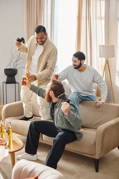 Três homens alegres e bonitos de raças diferentes desfrutar de tempo de qualidade juntos em um ambiente acolhedor sala de estar. — Fotografia de Stock