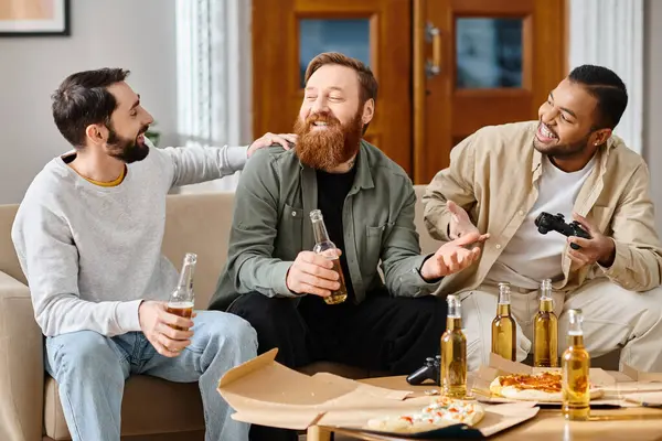Tres hombres guapos y alegres de diferentes razas, en atuendo casual, disfrutando de las bebidas y la compañía de los demás en una mesa. - foto de stock