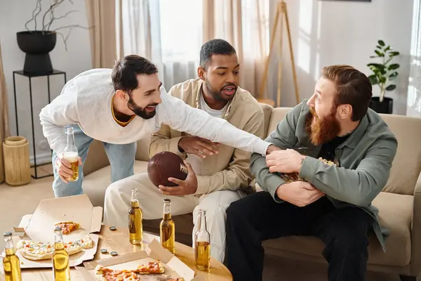 Trois amis gais et interracial en tenue décontractée s'assoient autour d'une table, riant et partageant pizza et bière. — Photo de stock