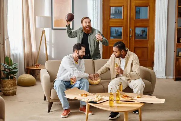 Три весёлых, красивых мужчины разных рас наслаждаются компанией друг друга на диване, одеваясь непринужденно дома.. — стоковое фото