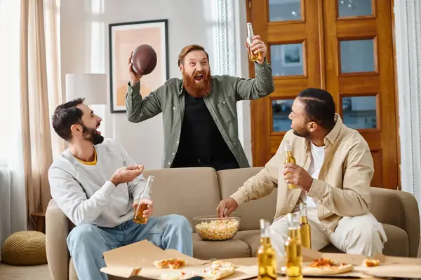Трое веселых, красивых мужчин разных национальностей лежат дома на диване, наслаждаясь друг другом в повседневной одежде. — стоковое фото