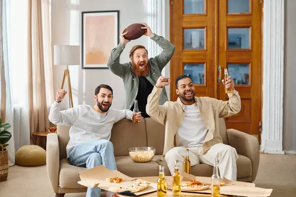 Tres hombres alegres, interracial en atuendo casual se sientan juntos en la parte superior de un sofá, disfrutando de un gran momento en compañía de los demás. — Stock Photo