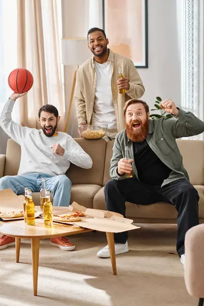 Три весёлых, красивых мужчины разных рас наслаждаются друг другом в уютной гостиной, демонстрируя дружбу и расслабление.. — стоковое фото