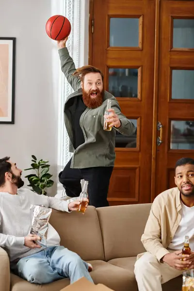 Drei fröhliche, gut aussehende Männer verschiedener Rassen sitzen auf einer Couch und genießen in legerer Kleidung eine tolle Zeit miteinander. — Stockfoto