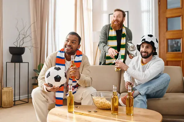 Trois hommes beaux et joyeux en tenue décontractée partageant rires et compagnie dans un cadre chaleureux et invitant salon. — Photo de stock