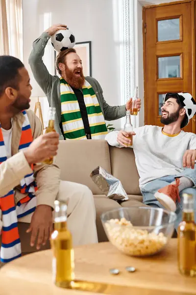 Tres hombres guapos y alegres de diferentes razas comparten un momento alegre juntos en un sofá en casa. - foto de stock