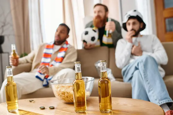 Three diverse, cheerful men enjoy each others company around a table, sharing bottles of beer. — Stock Photo