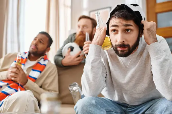 Три разнообразных, стильных мужчины в повседневной одежде наслаждаются временем смеха и разговоров, сидя на диване. — стоковое фото