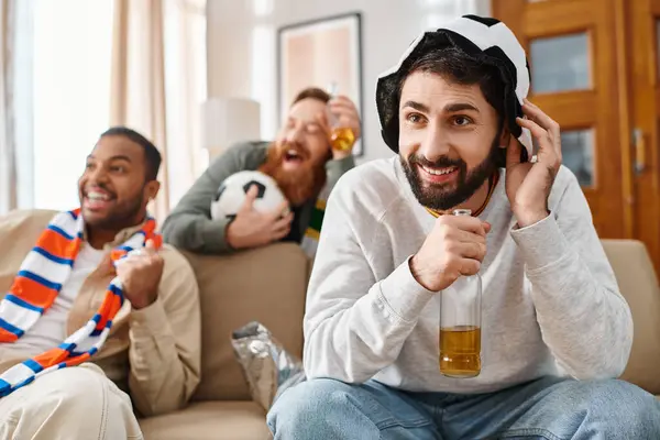Three cheerful, handsome men of different ethnicities in casual attire bonding and having a great time together on top of a couch. — Stock Photo