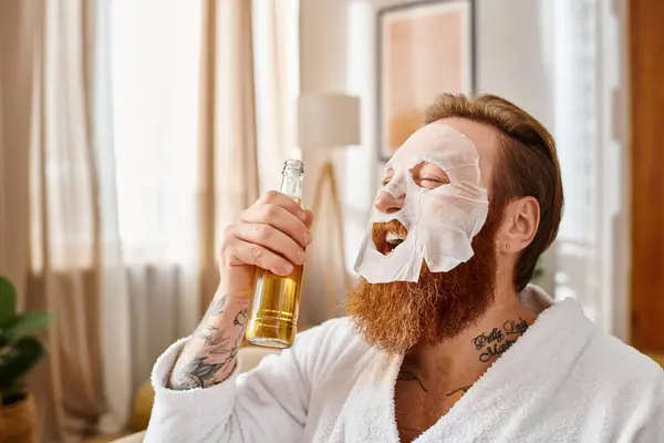 Um homem com uma máscara facial segura uma garrafa de álcool, incorporando relaxamento e autocuidado enquanto desfruta de um momento de indulgência. — Fotografia de Stock