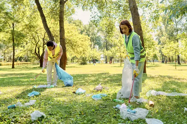 Socially active diverse loving couple in safety vests and gloves cleaning park together on the grass. — Stock Photo