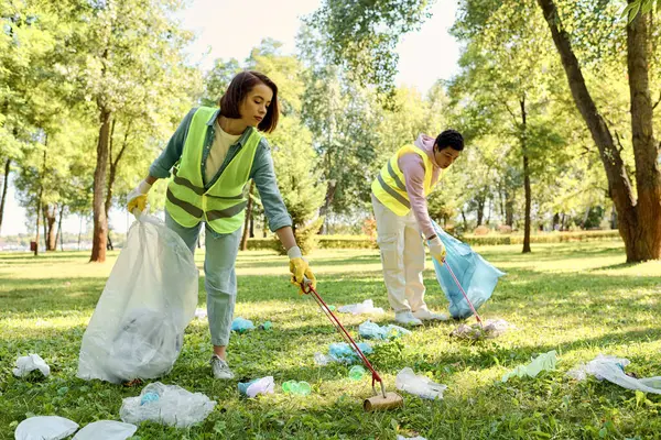 Diverse loving couple in safety vests and gloves standing together in the grass while cleaning the park. — Stock Photo