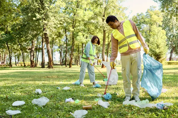 Різноманітна пара жилетів і рукавичок люблять чистити пишний парк разом, демонструючи свою турботу про навколишнє середовище. — стокове фото