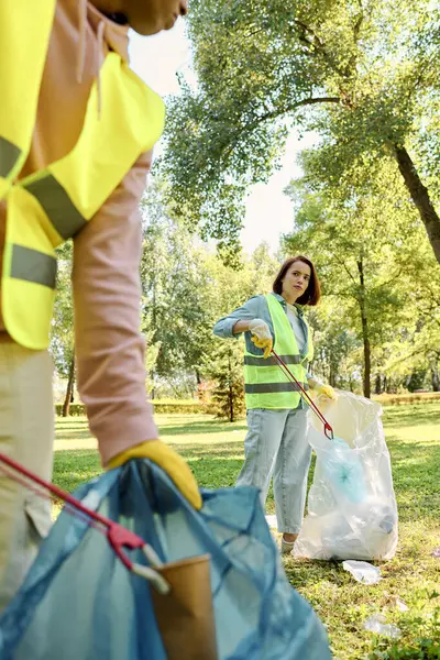 Diverso casal amoroso apaixonadamente limpar um parque enquanto vestindo luvas de segurança. — Fotografia de Stock
