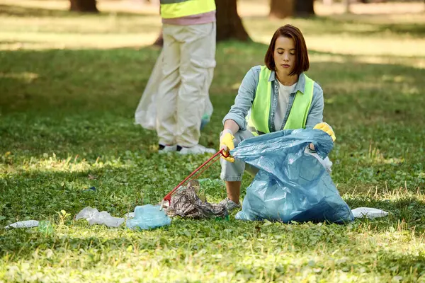 Pareja multicultural trabajadora y trabajadora que limpia apasionadamente un parque mientras usa guantes de seguridad. - foto de stock