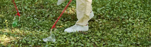 Eine Person steht im Gras und reinigt Plastikbecher vom Gras — Stockfoto