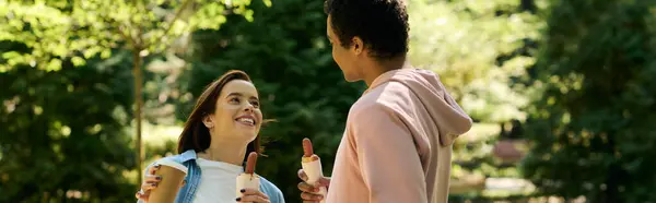 A diverse couple in vibrant attires standing together in a peaceful park setting, sharing a loving moment. — Stock Photo