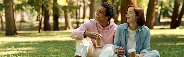 Diverse couple in vibrant attire enjoying a peaceful moment together as they sit on the lush green grass in a park. — Stock Photo