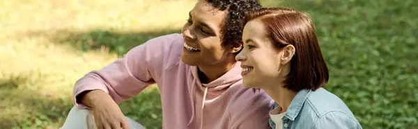 Um casal amoroso em trajes vibrantes se senta perto um do outro em um parque, irradiando felicidade e conexão. — Fotografia de Stock