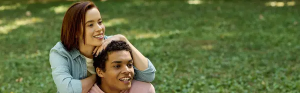 Un homme s'assoit joyeusement sur les épaules d'une femme, formant un lien unique et aimant dans un parc animé. — Photo de stock