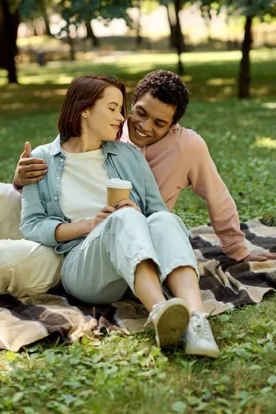 Чоловік і жінка у яскравому вбранні сидять на ковдрі в парку, насолоджуючись компанією один одного серед краси природи. — стокове фото