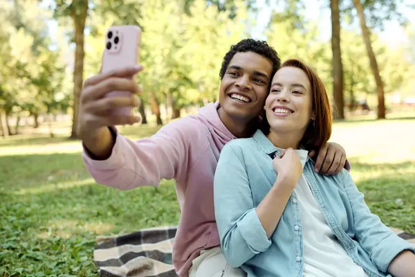 A loving couple, dressed vibrantly, capturing a joyful moment together with a selfie in a park. — Stock Photo