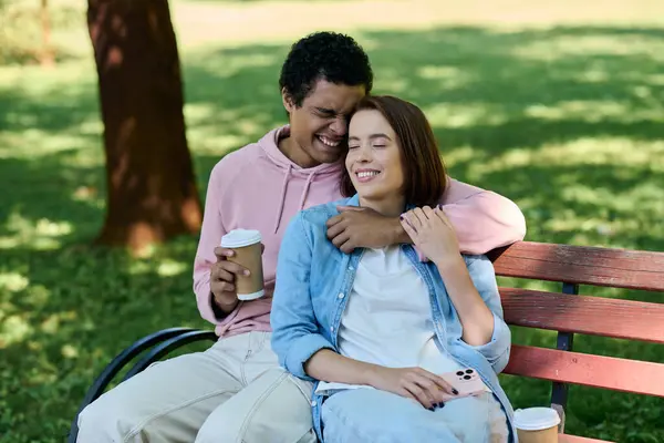 Un couple diversifié en tenue vibrante se détend sur un banc de parc, profitant de l'autre compagnie par une journée ensoleillée. — Photo de stock