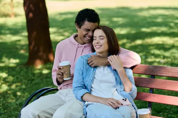 A diverse couple in vibrant attire relaxes on a park bench, enjoying each others company on a sunny day. — Stock Photo