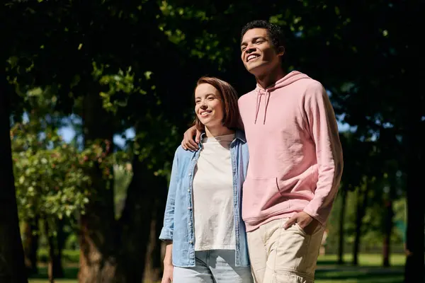 Un homme et une femme, vêtus de vêtements colorés, se tiennent ensemble dans un parc, montrant affection et unité. — Photo de stock