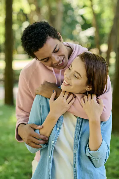 A man wearing vibrant attire holds a woman in a loving embrace in a beautiful park setting. — Stock Photo