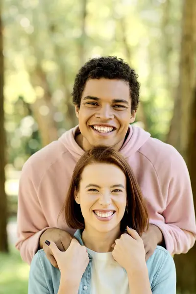 Una pareja diversa en traje vibrante sonriendo brillantemente para la cámara mientras disfrutan de un día juntos en el parque. - foto de stock