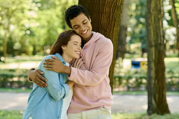 A man in vibrant attire hugs a woman lovingly, surrounded by the beauty of a park. — Stock Photo