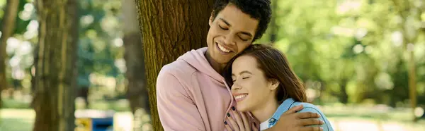 Una pareja diversa, vestida vibrantemente, compartiendo un abrazo amoroso en un entorno de parque. - foto de stock