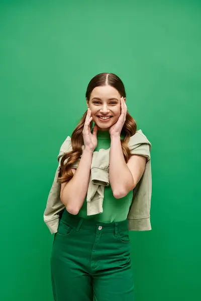 Une jeune femme élégante dans la vingtaine posant devant un fond vert luxuriant dans un décor de studio. — Photo de stock