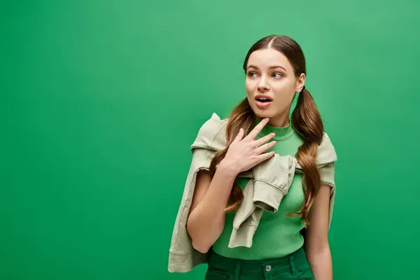 Eine junge Frau in ihren Zwanzigern in einem grünen Hemd hält ihre Hände friedlich auf der Brust in einem Studio-Setting. — Stockfoto