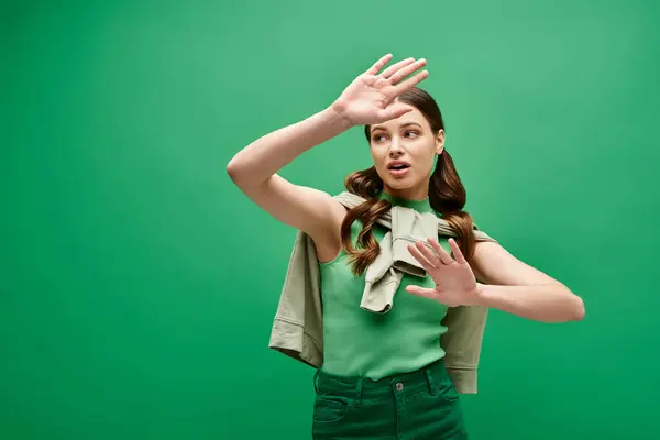 Eine junge Frau in ihren Zwanzigern, in ein grünes Hemd gehüllt, macht im Studio eine anmutige Handgeste. — Stockfoto