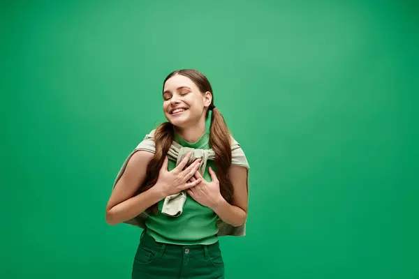 A young woman in her 20s beams with joy, holding her hands together in a gesture of happiness. — Stock Photo