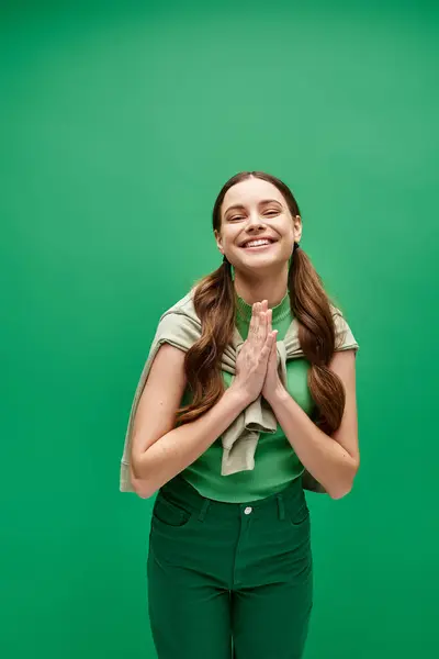 A young beautiful woman in her 20s standing in front of a vibrant green background in a studio setting. — Stock Photo