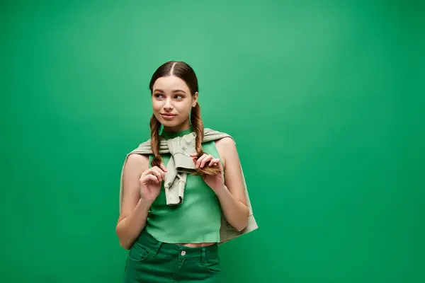 A young woman in her 20s with beautiful long hair posing in a studio setting with a green backdrop. — Stock Photo