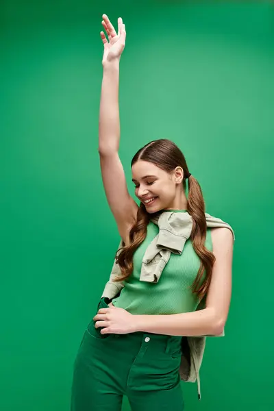 Счастливая молодая красивая девушка в возрасте 20 лет в зеленой рубашке и зеленых штанах в студии. — стоковое фото