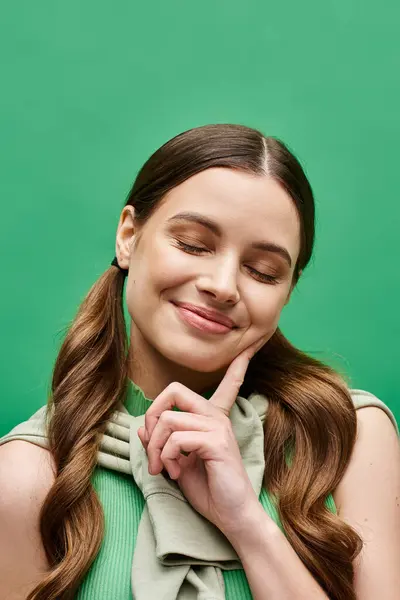 Eine junge Frau mit langen Haaren posiert anmutig in einem leuchtend grünen Hemd in einem Studio-Setting. — Stockfoto
