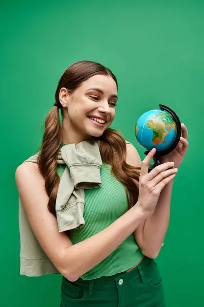 Une jeune femme dans la vingtaine tient un petit globe dans ses mains, dépeignant les soins et le souci du monde. — Photo de stock